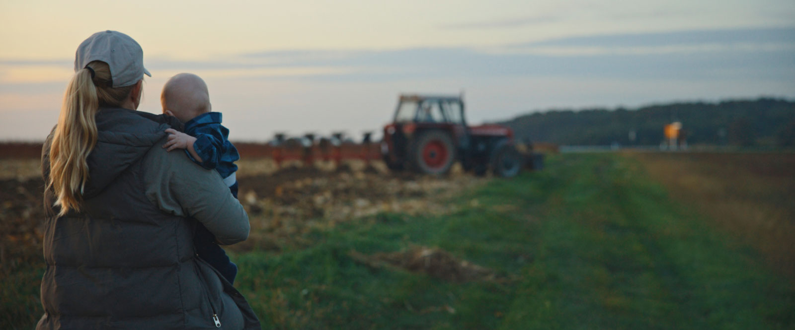 Mom holding an infant while looking out over a farm field